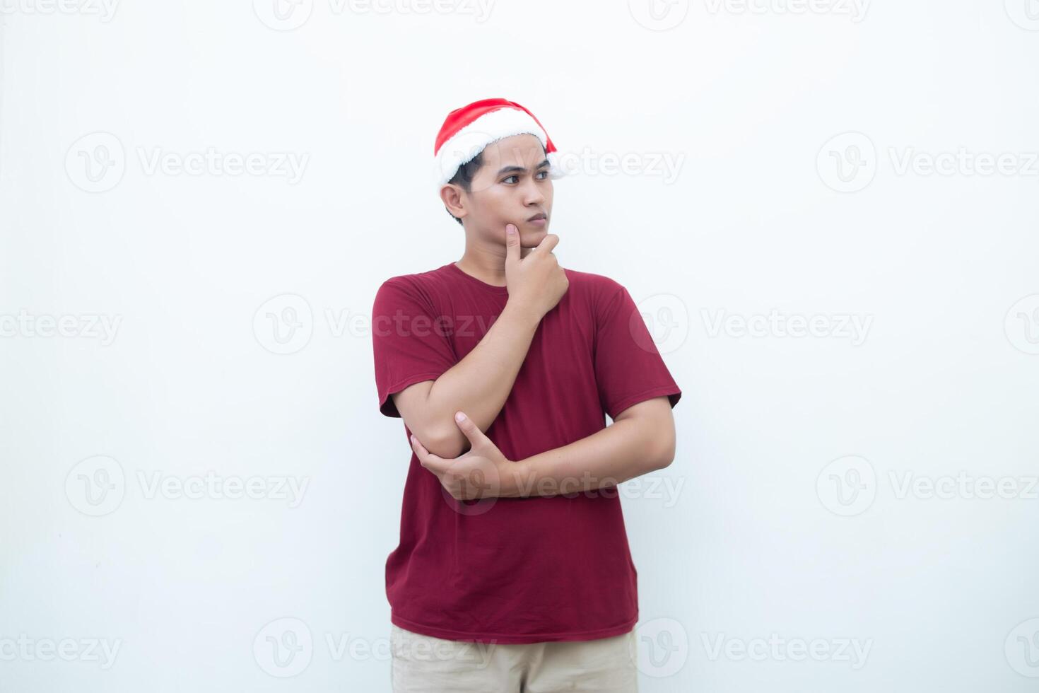 Young Asian man wearing a Santa Claus hat smiling, shock and pointing to her side isolated by white background for visual communication photo