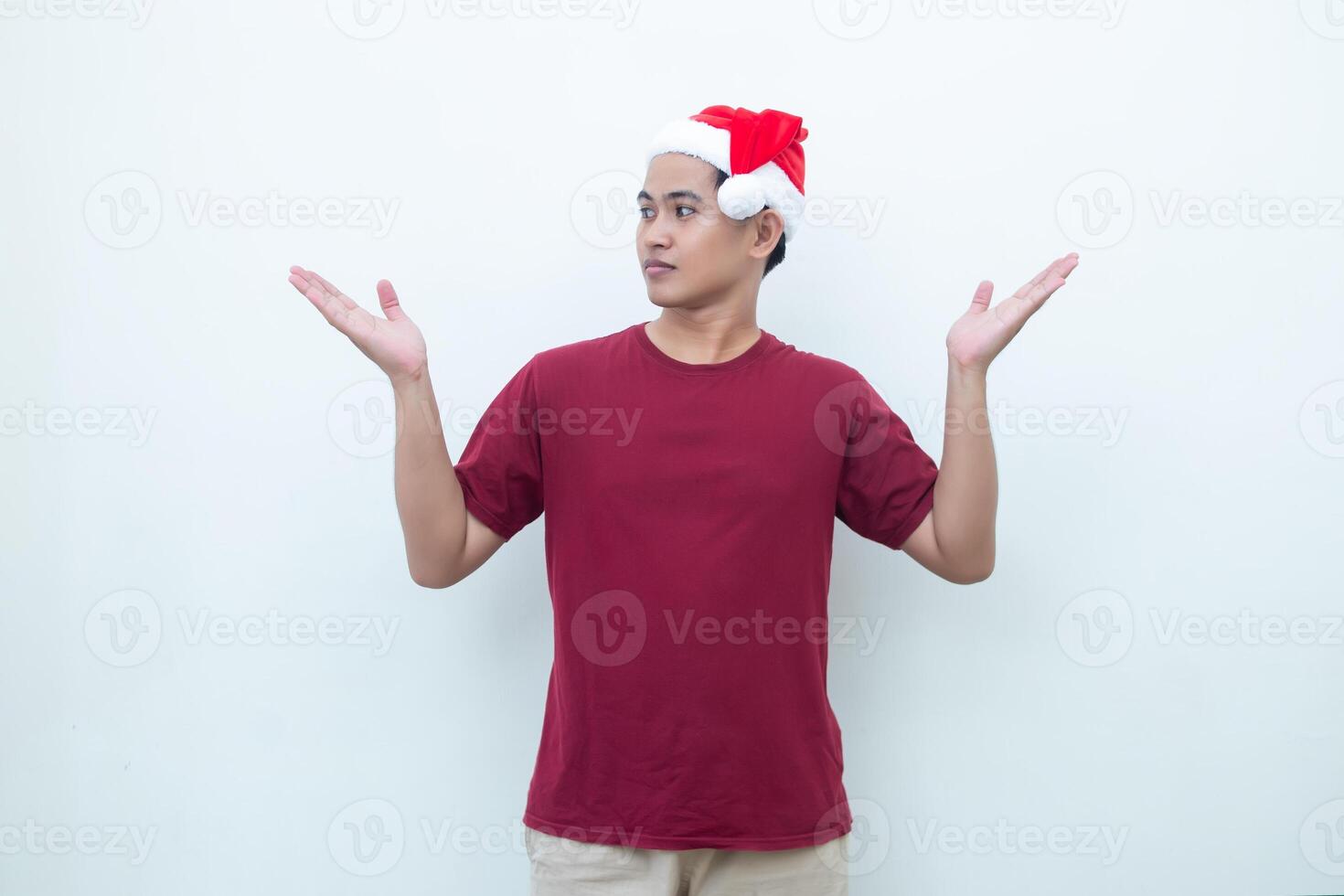 Young Asian man wearing a Santa Claus hat smiling, shock and pointing to her side isolated by white background for visual communication photo