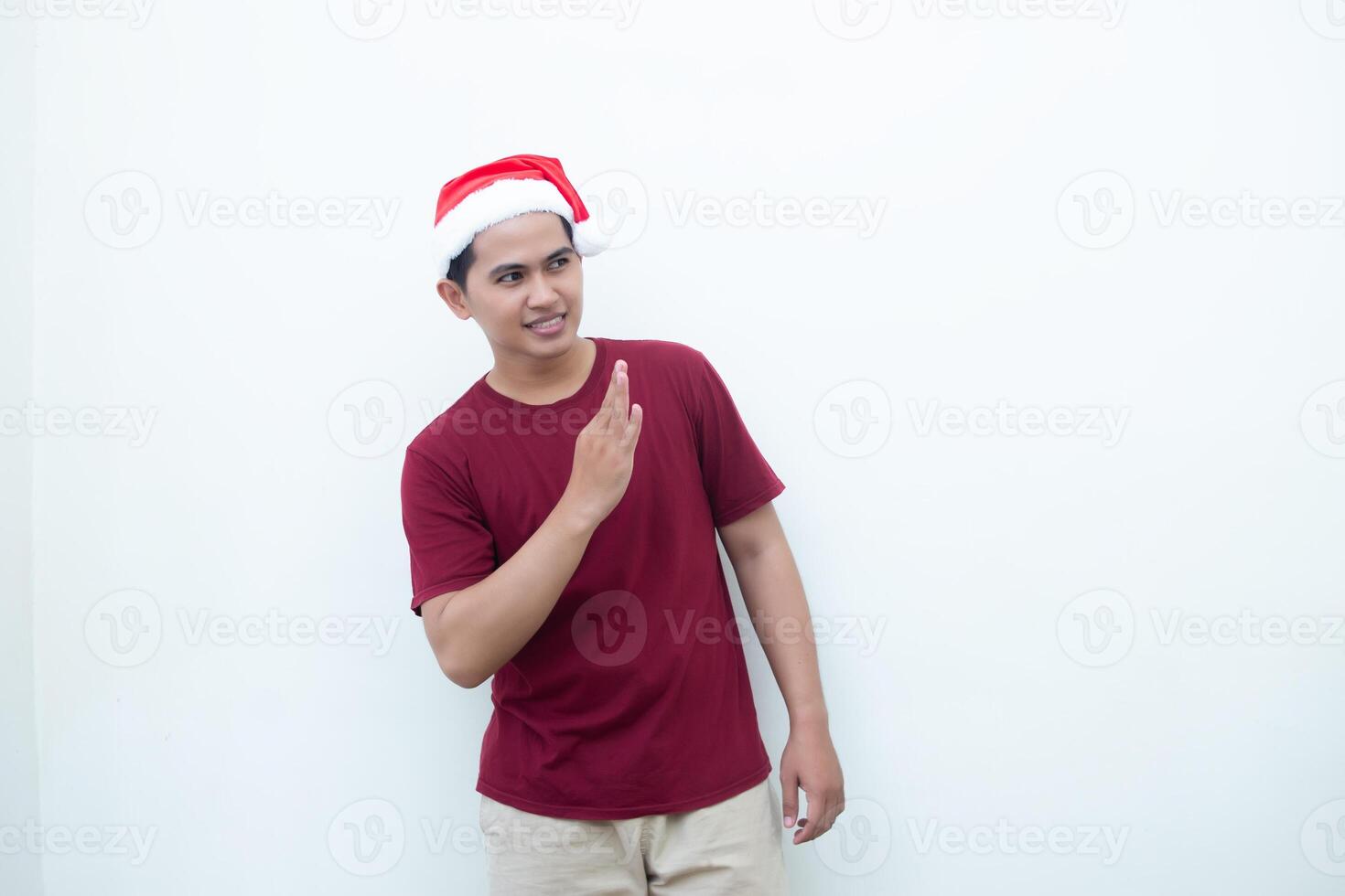 Young Asian man wearing a Santa Claus hat with a hand making the ok gesture isolated by a white background for visual communication photo