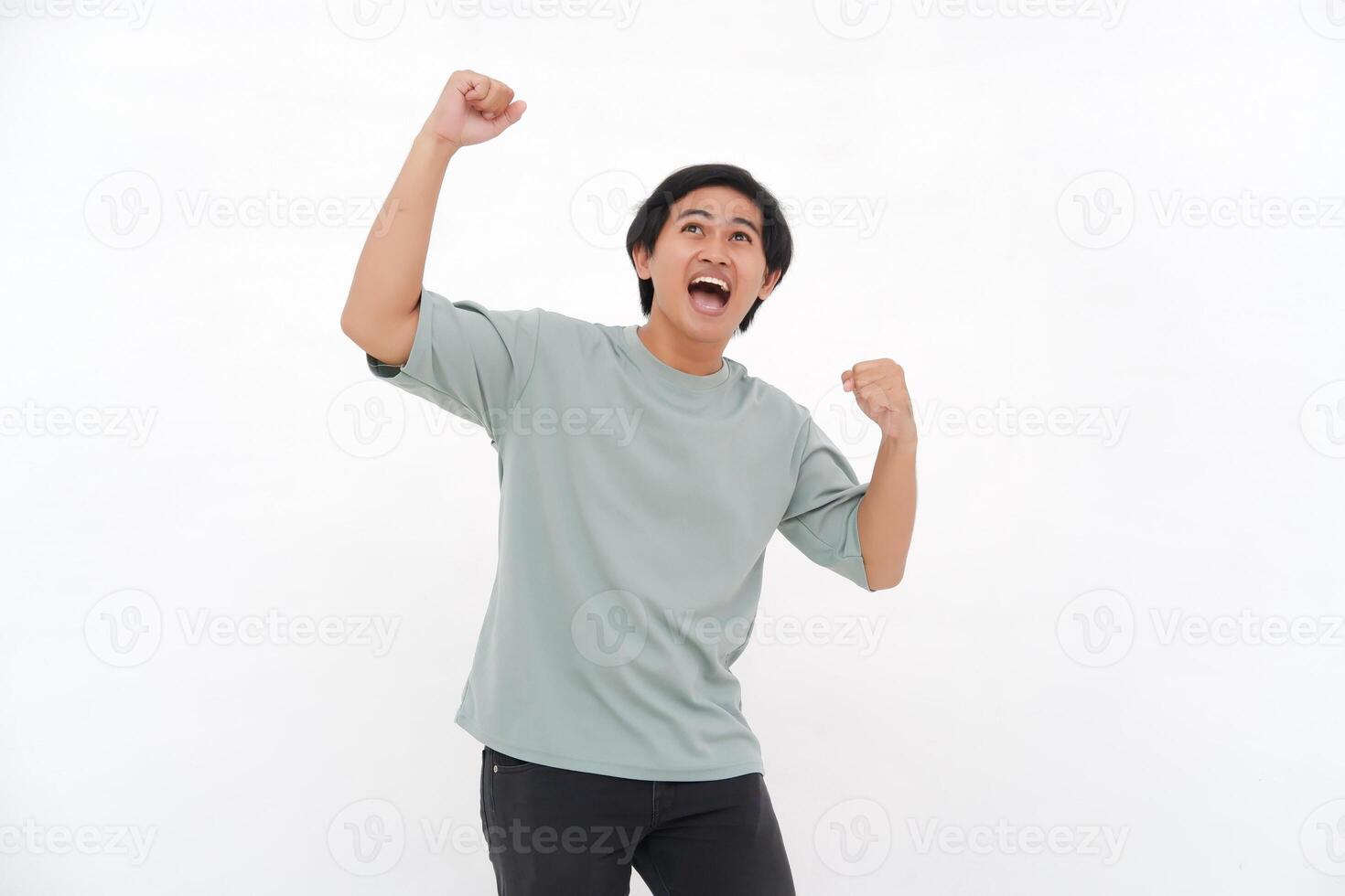 Young Asian man with an enthusiastic expression as if feeling victorious, depicting a sense of great satisfaction. photo