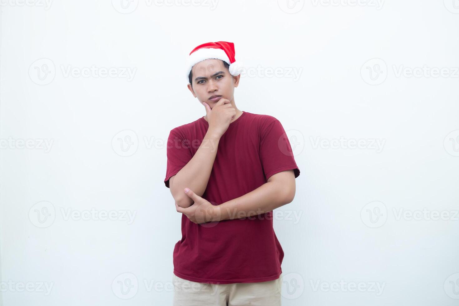 Young Asian man wearing a Santa Claus hat smiling, shock and pointing to her side isolated by white background for visual communication photo