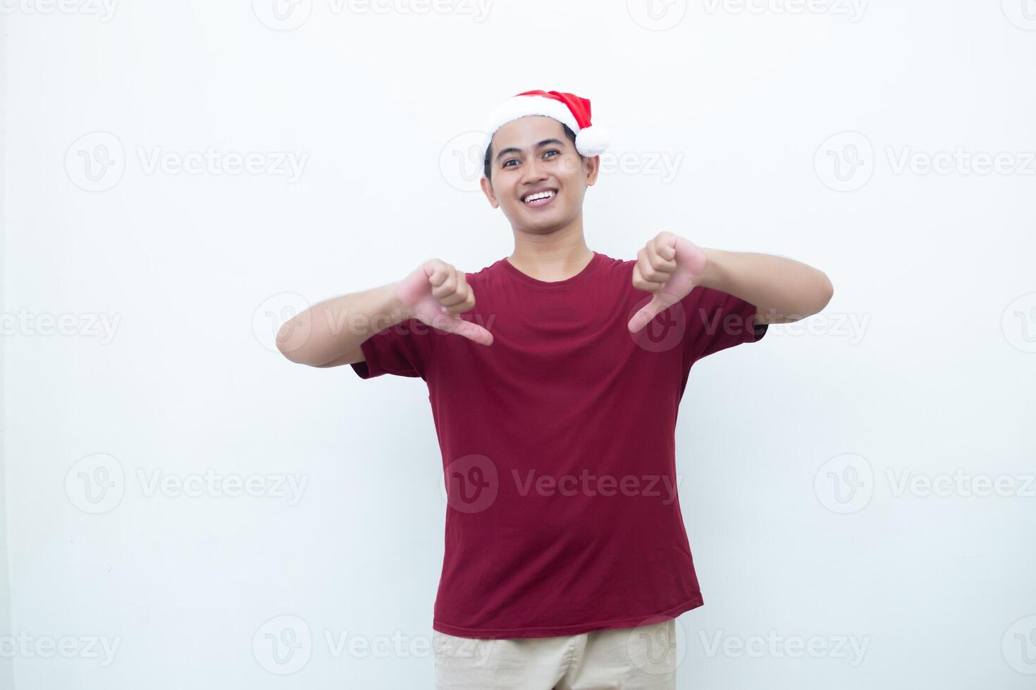 Young Asian man wearing a Santa Claus hat smiling, shock and pointing to her side isolated by white background for visual communication photo