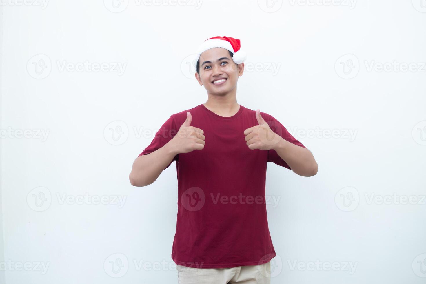 Young Asian man wearing a Santa Claus hat smiling, shock and pointing to her side isolated by white background for visual communication photo