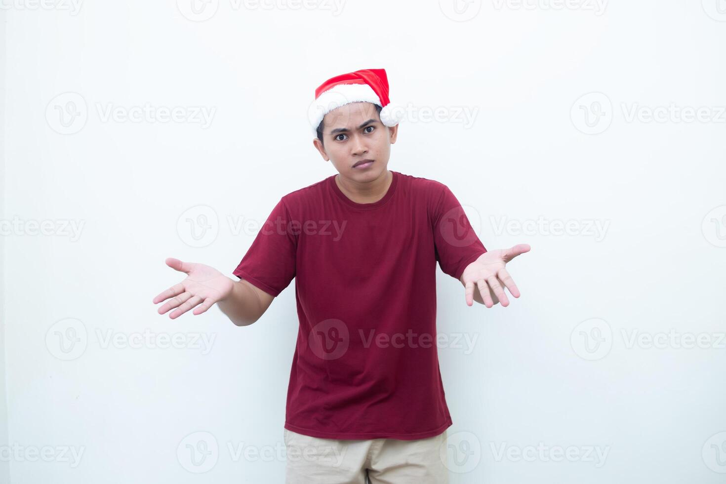 Young Asian man wearing a Santa Claus hat smiling, shock and pointing to her side isolated by white background for visual communication photo