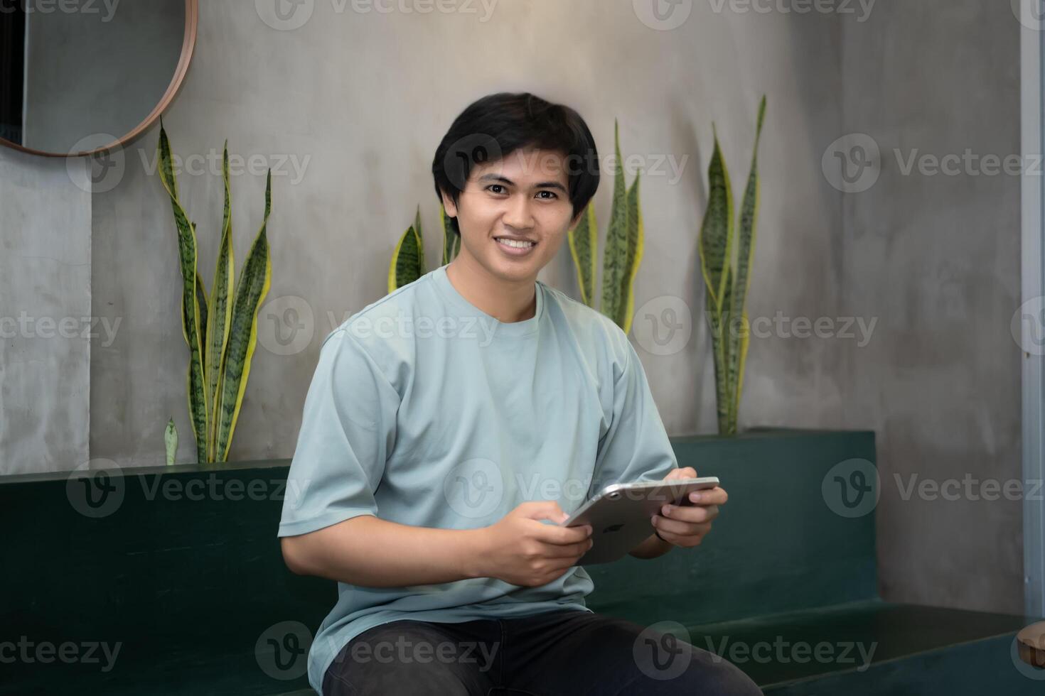 Potrait of Young Asian men holding a tablet PC in a cafe workplace with expressive faces photo