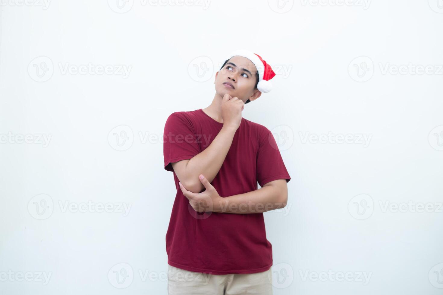 Young Asian man wearing a Santa Claus hat smiling, shock and pointing to her side isolated by white background for visual communication photo