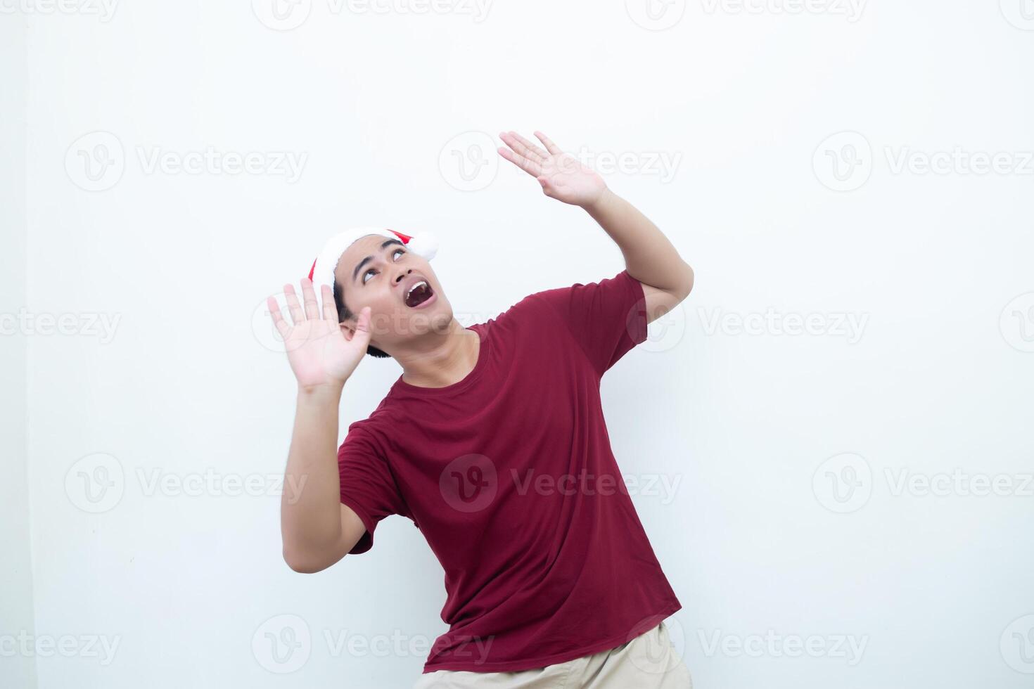 joven asiático hombre vistiendo un Papa Noel claus sombrero expresando conmoción y renuencia aislado por un blanco antecedentes para visual comunicación foto