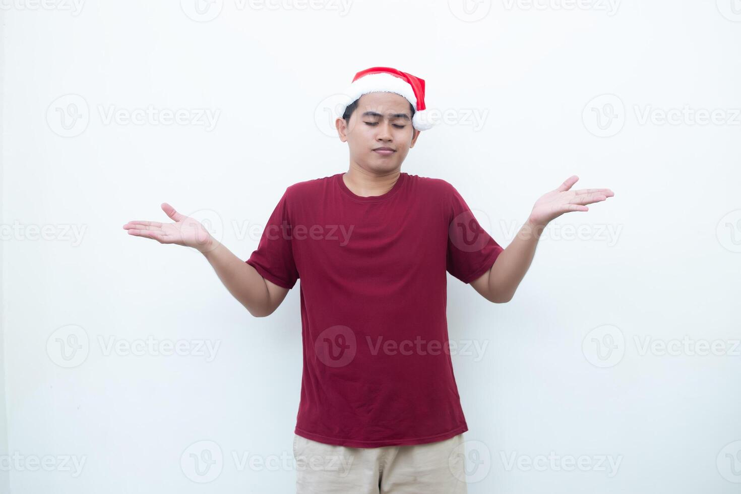Young Asian man wearing a Santa Claus hat smiling, shock and pointing to her side isolated by white background for visual communication photo