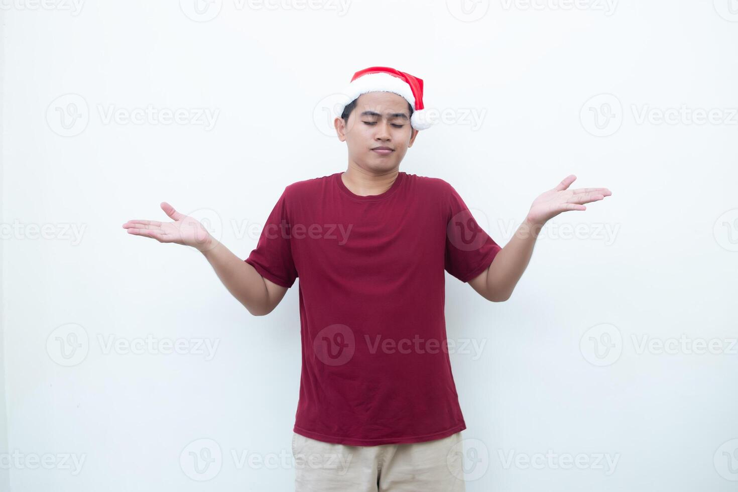 joven asiático hombre vistiendo un Papa Noel claus sombrero sonriente, conmoción y señalando a su lado aislado por blanco antecedentes para visual comunicación foto