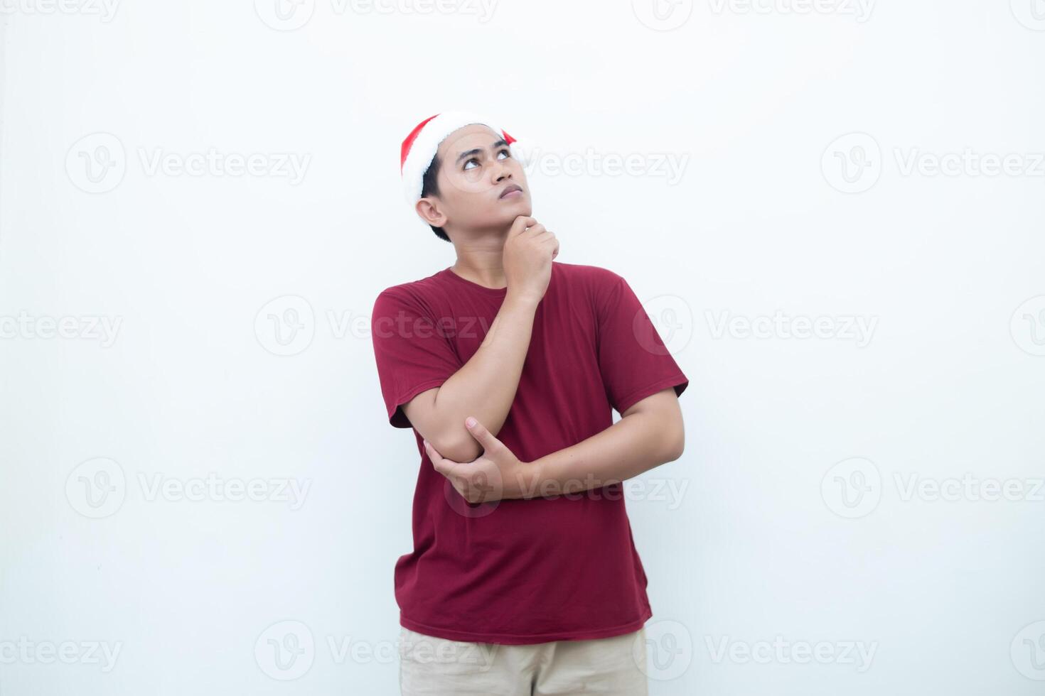 Young Asian man wearing a Santa Claus hat smiling, shock and pointing to her side isolated by white background for visual communication photo