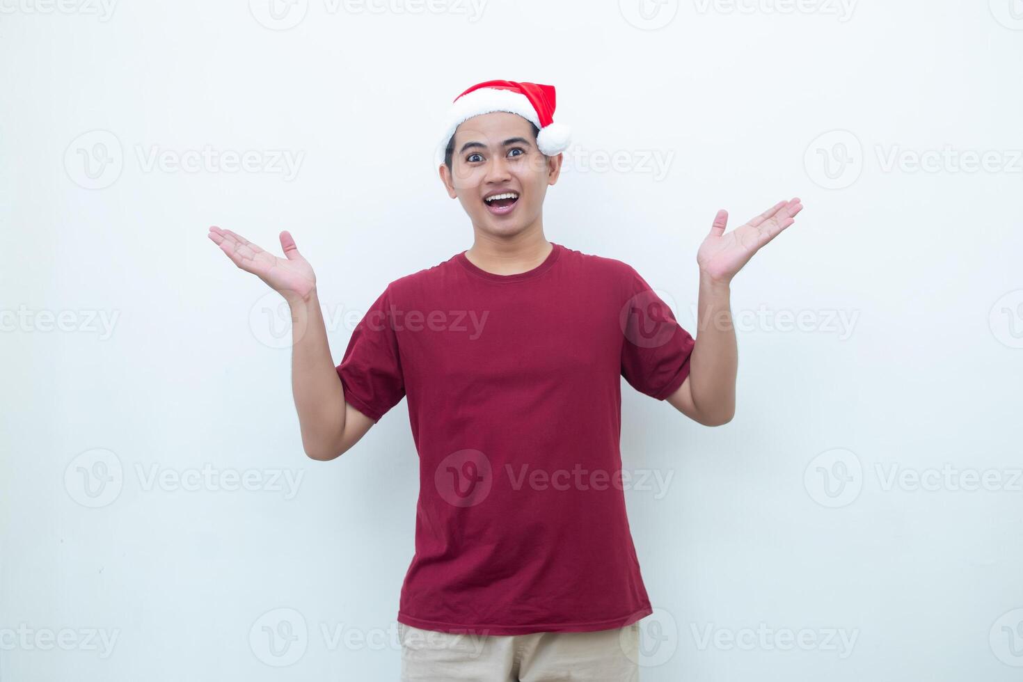 Young Asian man wearing a Santa Claus hat smiling, shock and pointing to her side isolated by white background for visual communication photo