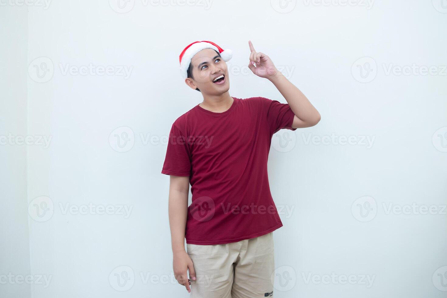 joven asiático hombre vistiendo un Papa Noel claus sombrero expresando confusión, pensamiento, y luego teniendo un idea, aislado por un blanco antecedentes para visual comunicación foto