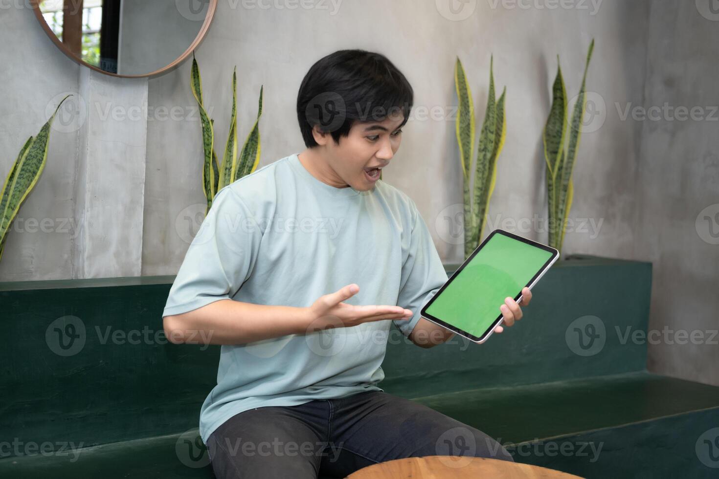 Potrait of Young Asian men holding a tablet PC in a cafe workplace with expressive faces photo