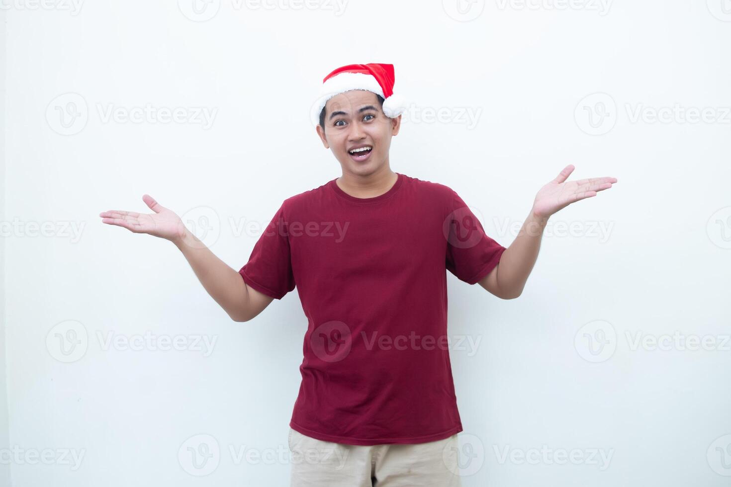 Young Asian man wearing a Santa Claus hat smiling, shock and pointing to her side isolated by white background for visual communication photo