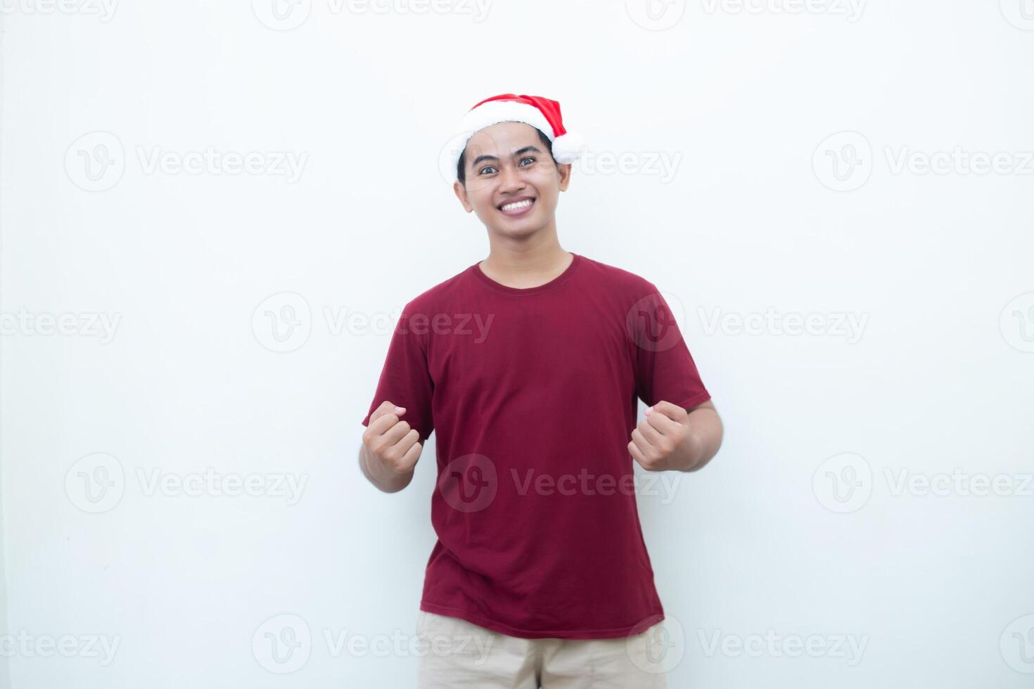 joven asiático hombre vistiendo un Papa Noel claus sombrero agarre ambos manos con entusiasmo y ira aislado por un blanco antecedentes para visual comunicación foto