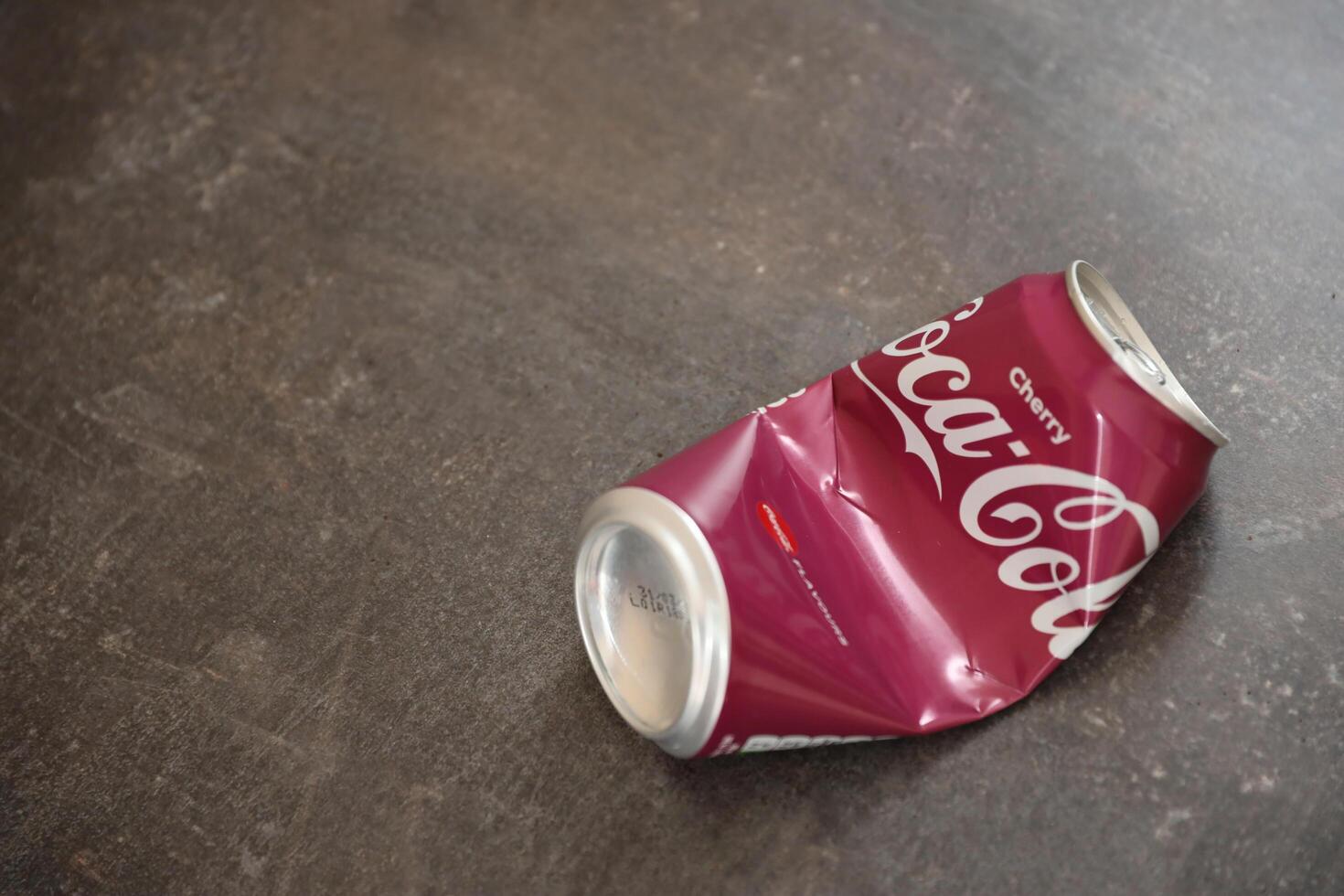 KYIV, UKRAINE - 4 MAY, 2023 Coca cola soft drink crumpled tin can with cherry flavour photo