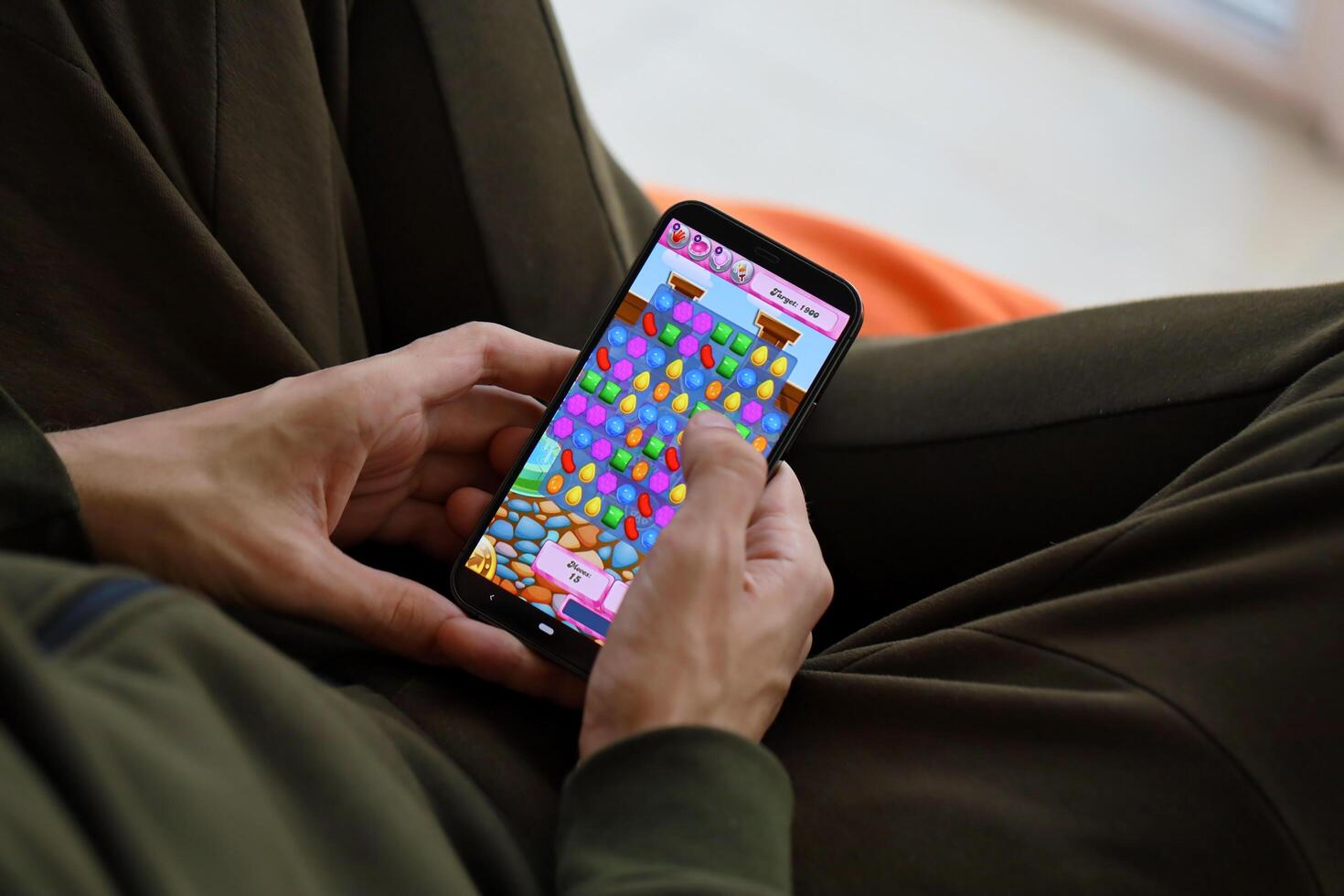 Candy Crush Saga mobile iOS game on iPhone 15 smartphone screen in male hands during mobile gameplay photo