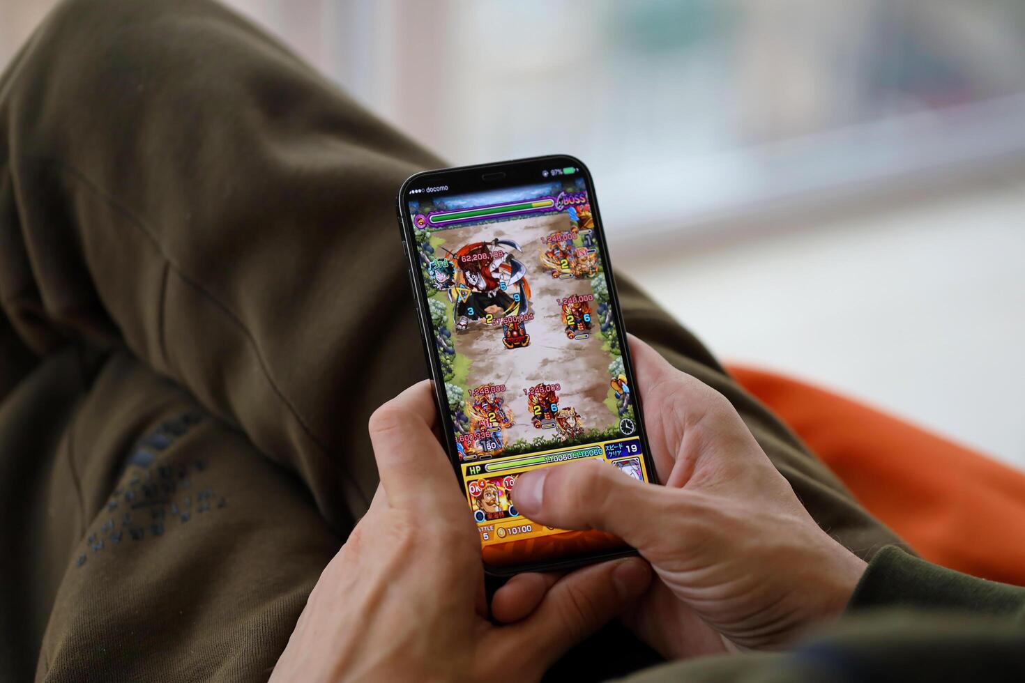 Monster Strike mobile iOS game on iPhone 15 smartphone screen in male hands during mobile gameplay photo