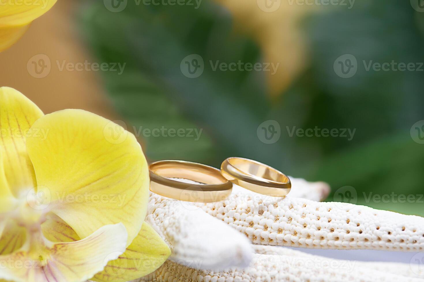 Wedding gold rings on white starfish with yellow orchid. Palm tree behind. Concept ceremony in hot tropical countries, newlyweds, just married, Valentine's Day, proposal. Copy space photo