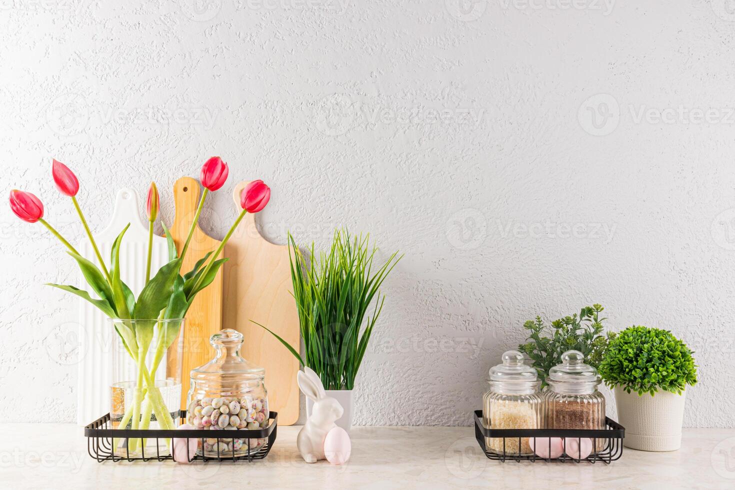 elegante cocina antecedentes decorado para Pascua de Resurrección día festivo. florero con tulipanes, en conserva plantas, huevos en soportes, cerámico conejos frente vista. foto