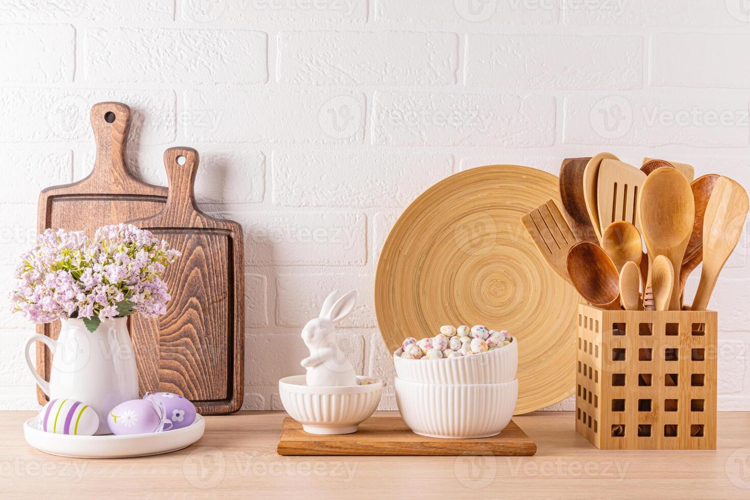 Kitchen wooden countertop with kitchen utensils and festive decorations for the spring Easter holiday. Front view. White brick wall. photo