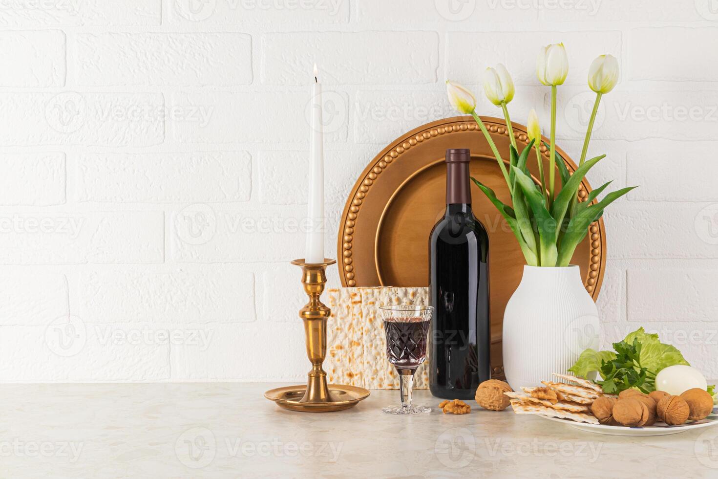 Concept of the Jewish Passover holiday. Spring celebration arrangement with a bottle of red wine, matzoth bread, a burning candle in a candlestick. photo