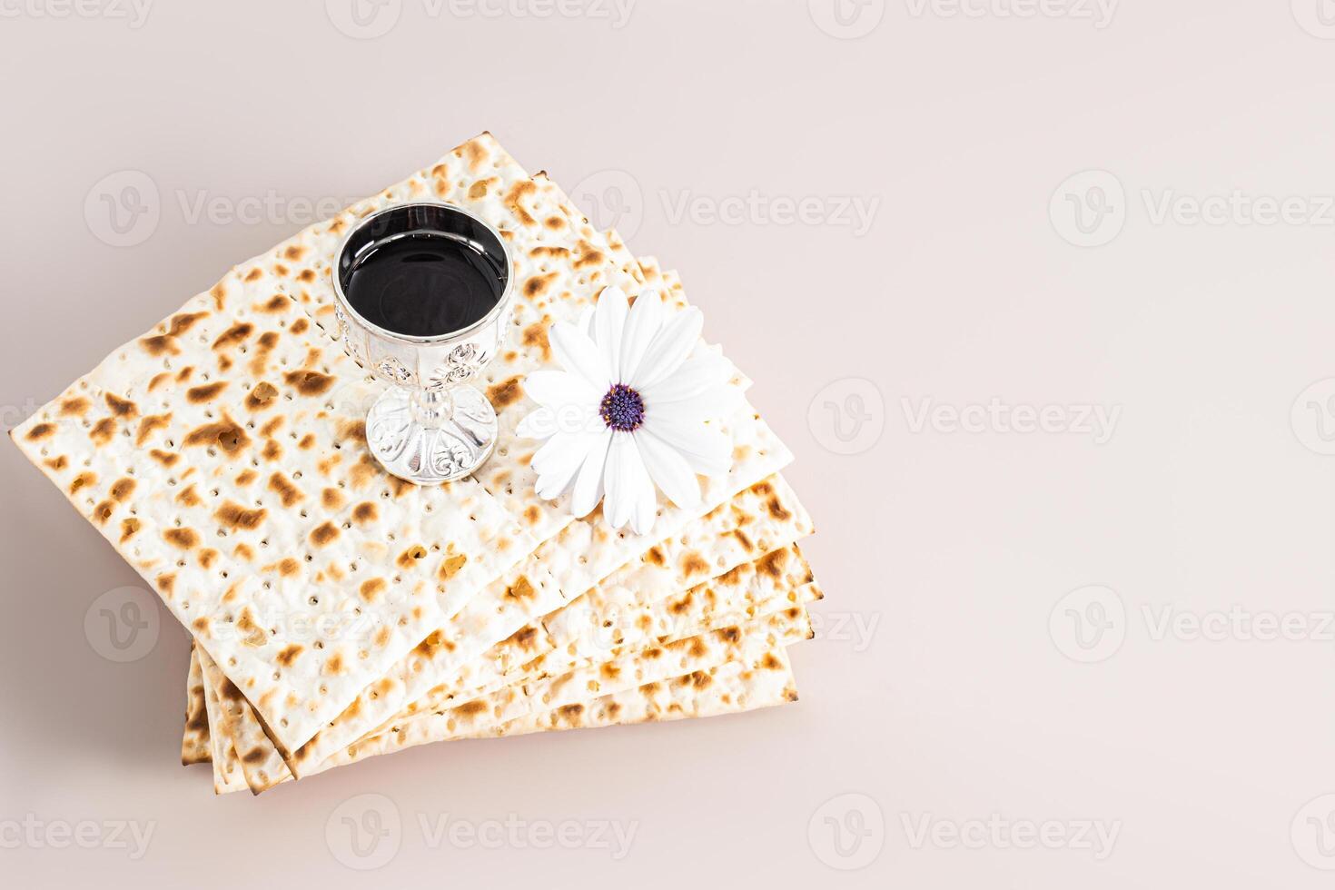 A stack of freshly baked matza and a silver shot glass with red wine and a spring flower. The holiday of the Jewish Passover. minimalism. pastel photo