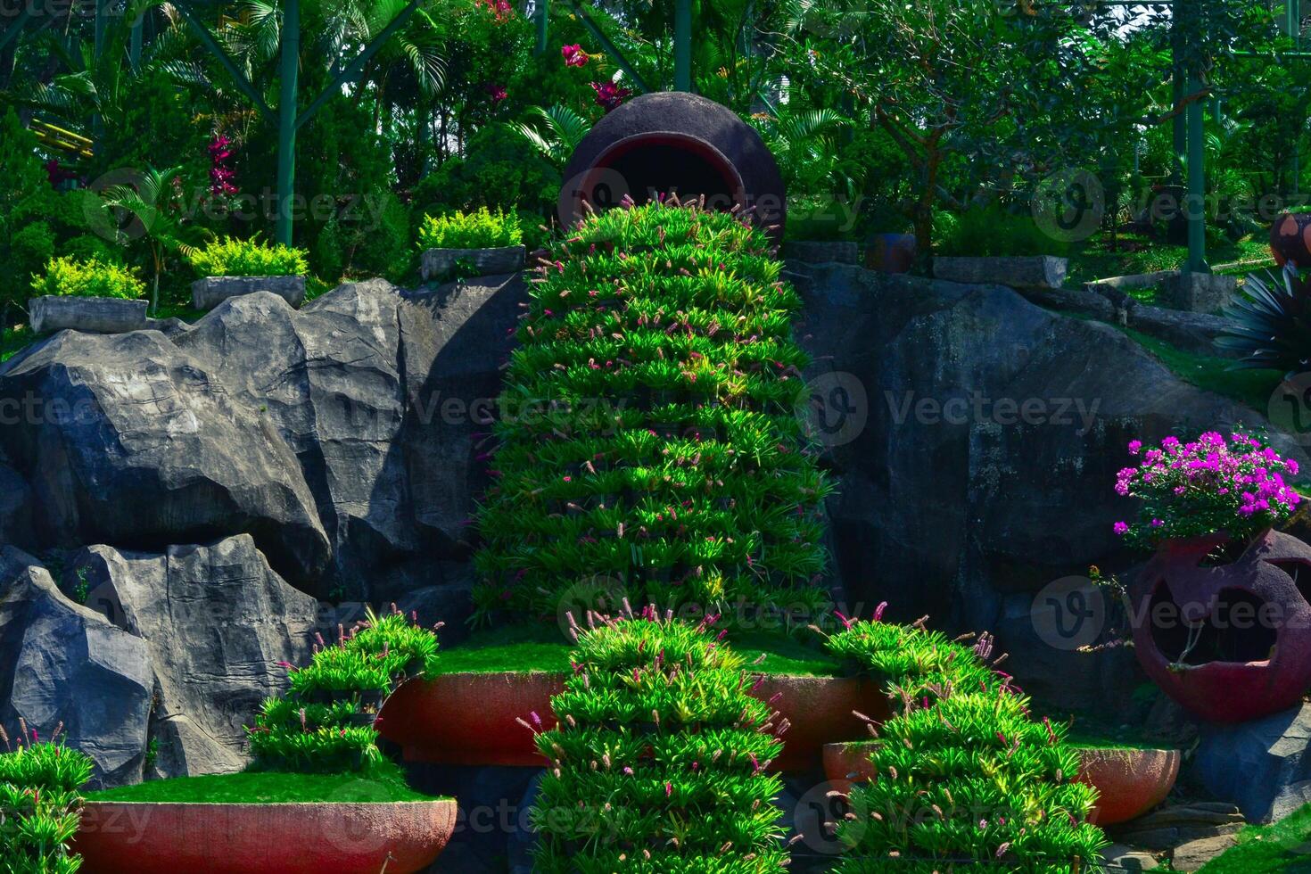 a green bush park with stone behind photo