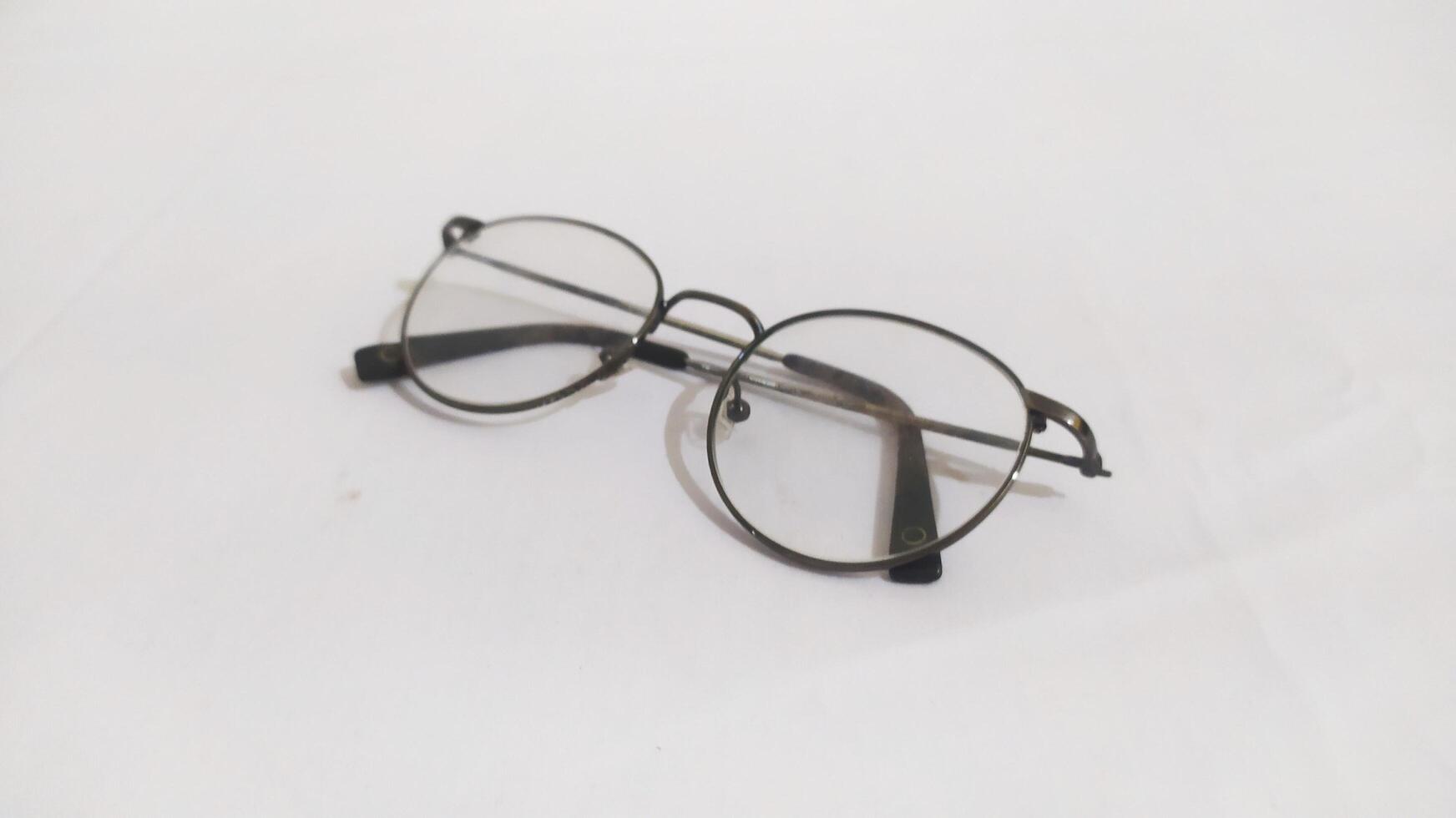 a pair of small glasses lying on the white surface photo