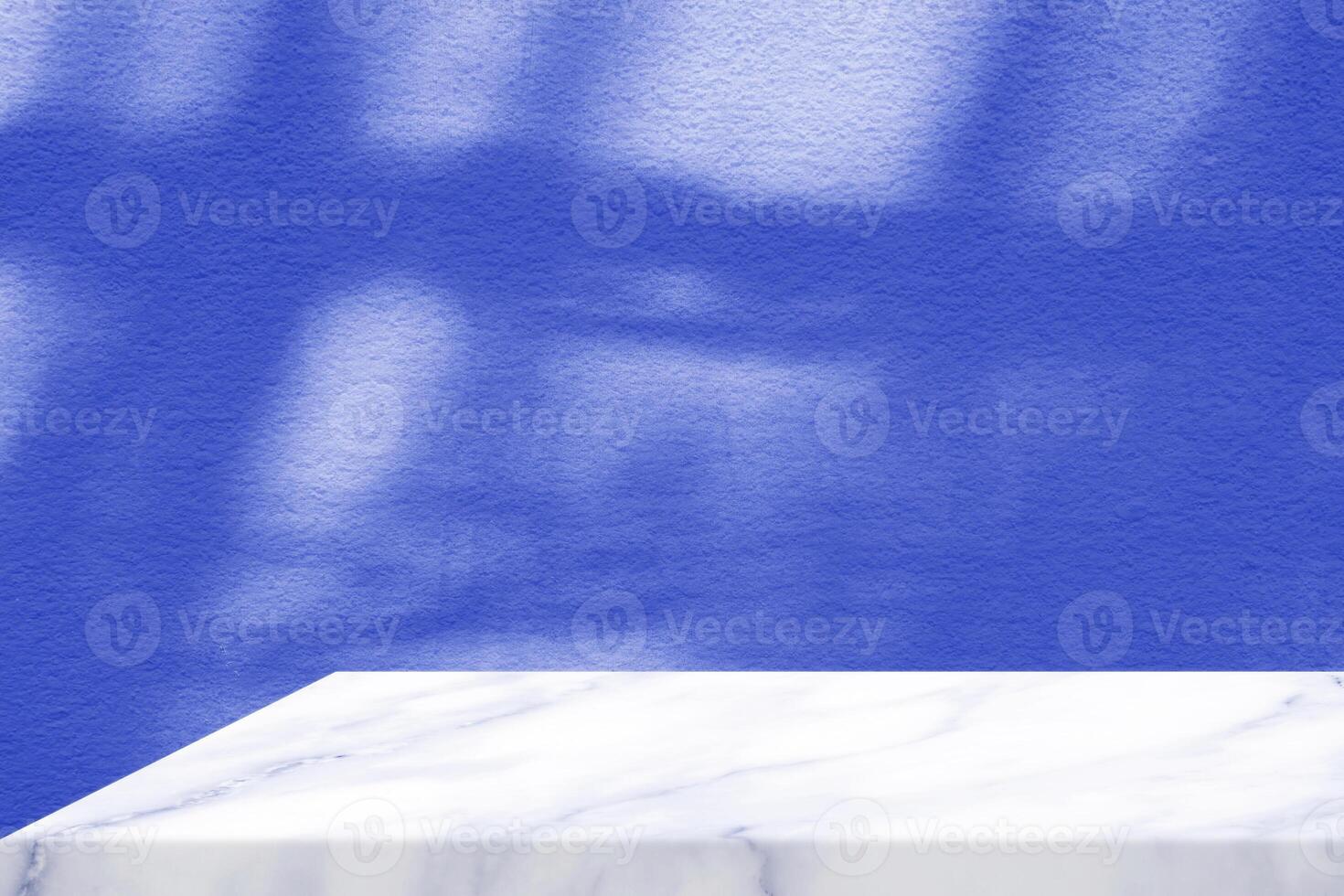 White Marble Table Corner with Light Beam, Shadow, and Spotlight on the Blue Concrete Wall Background, Suitable for Product Presentation Backdrop, Display, and Mock up. photo