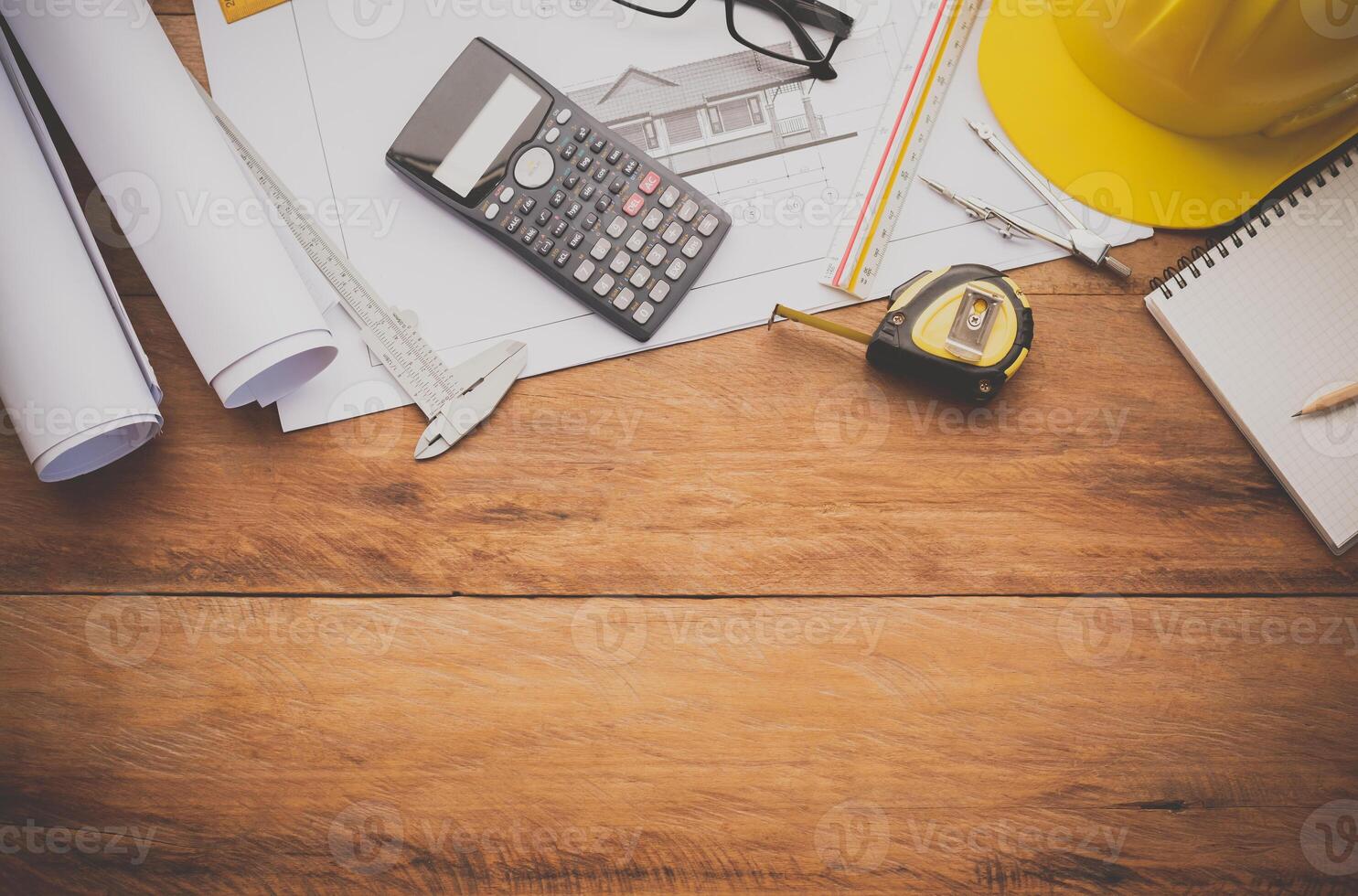 top view House blueprint and work equipment consisting of a calculator, compass, compass, helmet, placed on a wooden floor. concept equipment of the engineers working photo