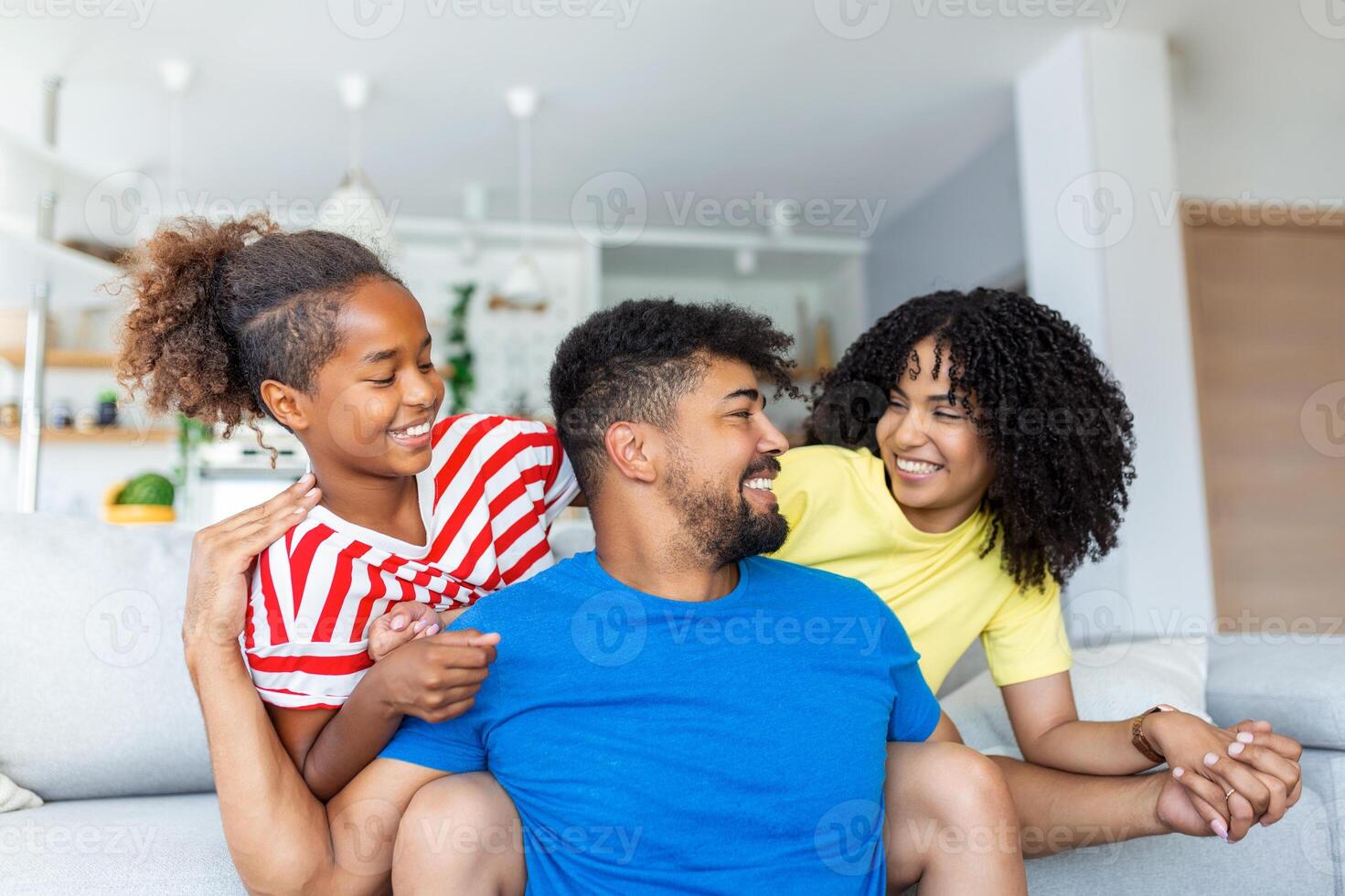 Portrait attractive multi-ethnic wife husband and kid indoors. Close up married couple with little pretty daughter sitting together smiling looking at camera. Concept friendly wellbeing happy family photo