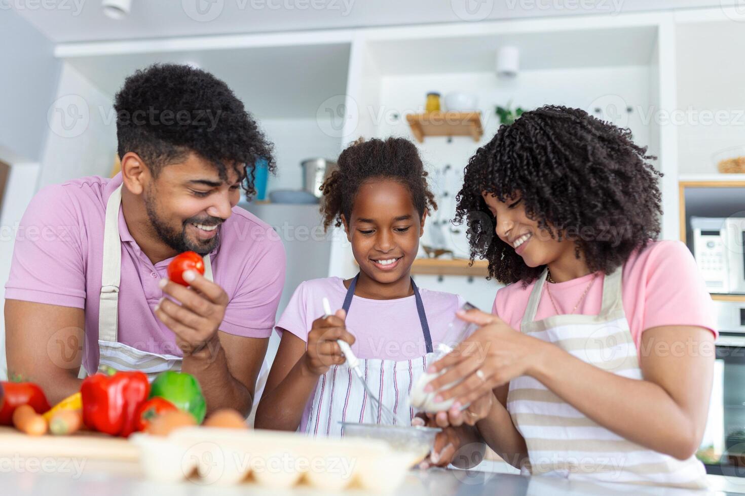 Shot of beautiful cute family having fun while cooking together in the kitchen at home. Cute little girl and her beautiful parents are smiling while cooking in kitchen at home photo
