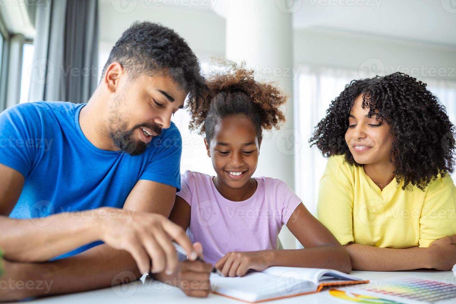 Multiethnic parents helping daughter with her homework at home. Young father and mother helping daughter study at living room. Little girl completing their exercises with the help of dad and mom. photo