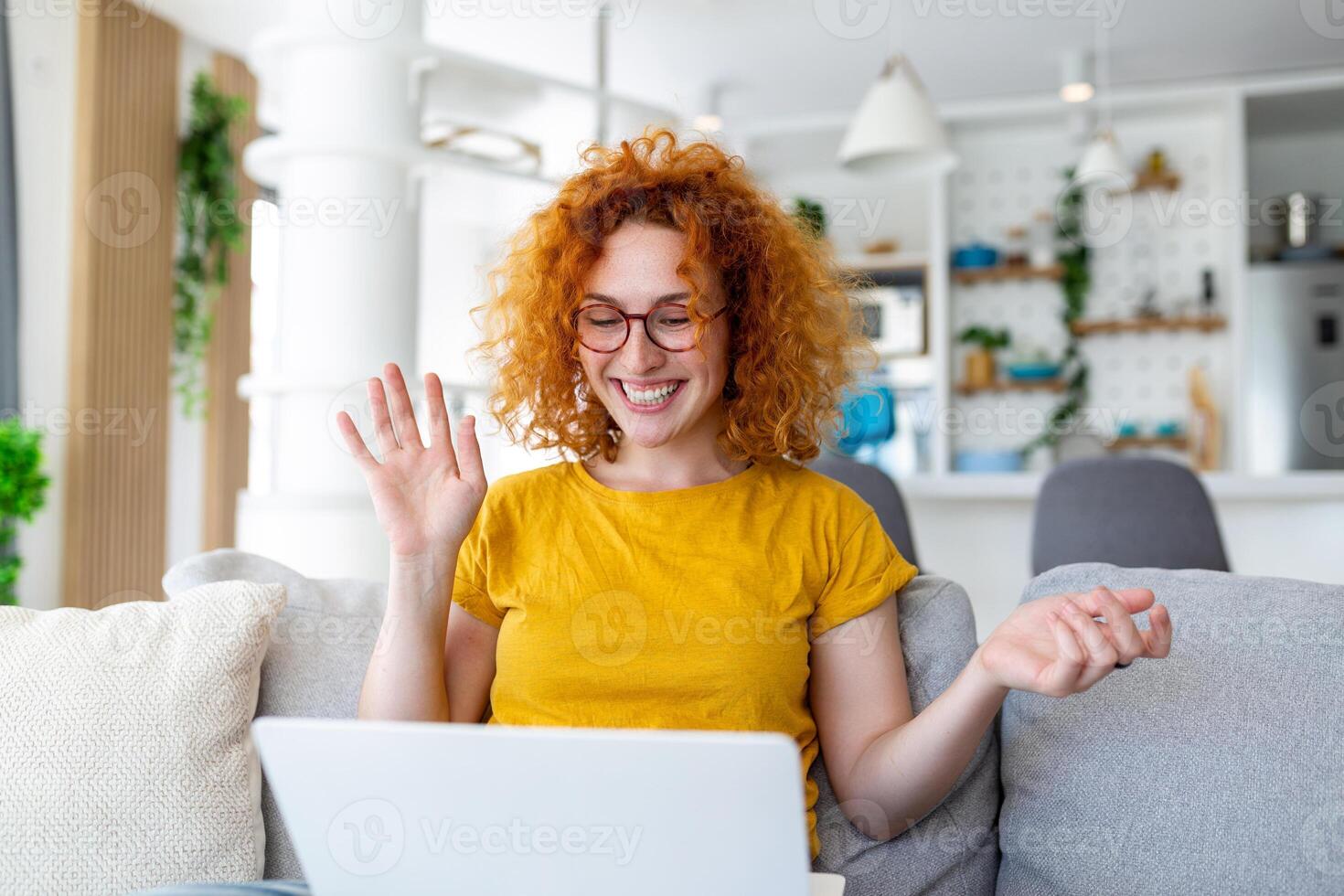 Happy young woman having fun doing video call using laptop in her home, waving hand video conference calling on laptop computer sit on sofa distance learn zoom online virtual meeting at home. photo