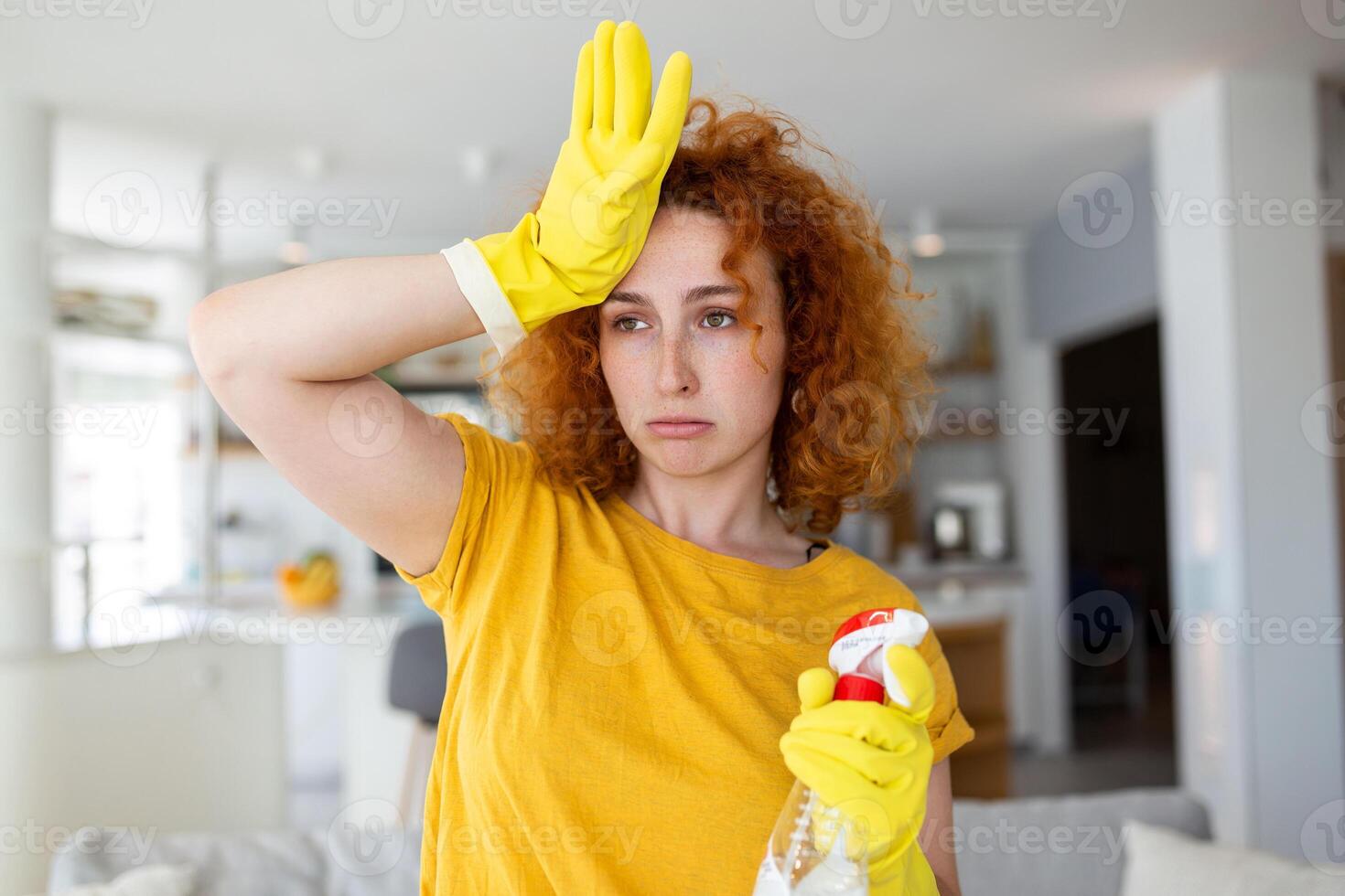 Portrait of young tired woman with rubber gloves resting after cleaning an apartment. Home, housekeeping concept. photo