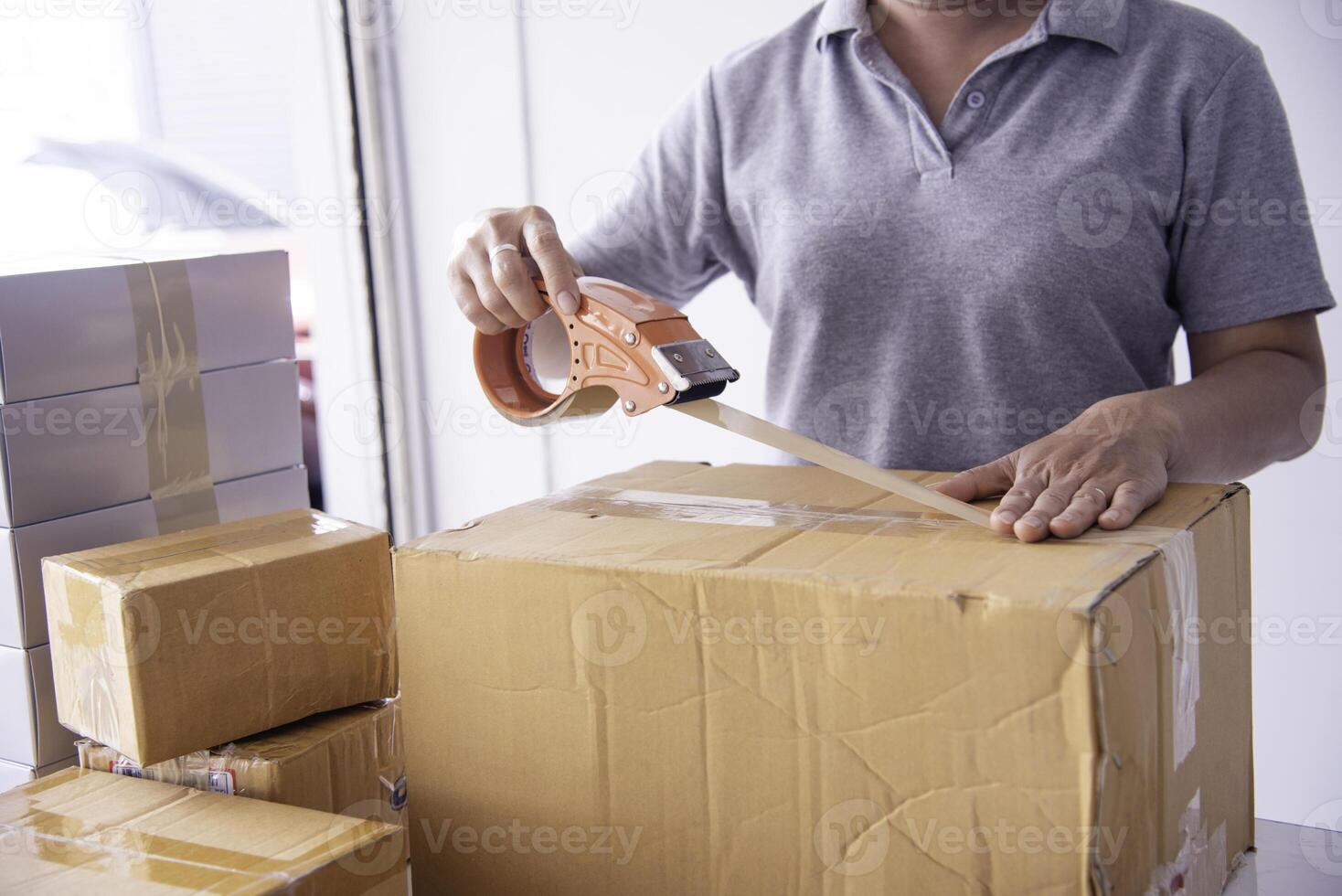 The staff is using the tape to pack the package goods to the customer. photo