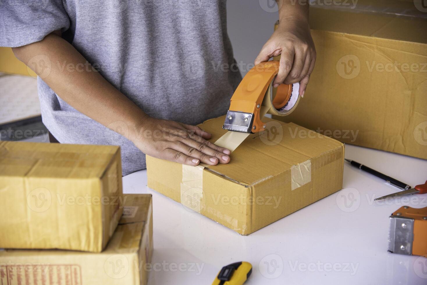 The staff is using the tape to pack the package goods to the customer. photo