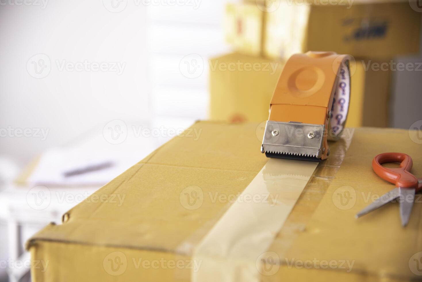 The staff is using the tape to pack the package goods to the customer. photo