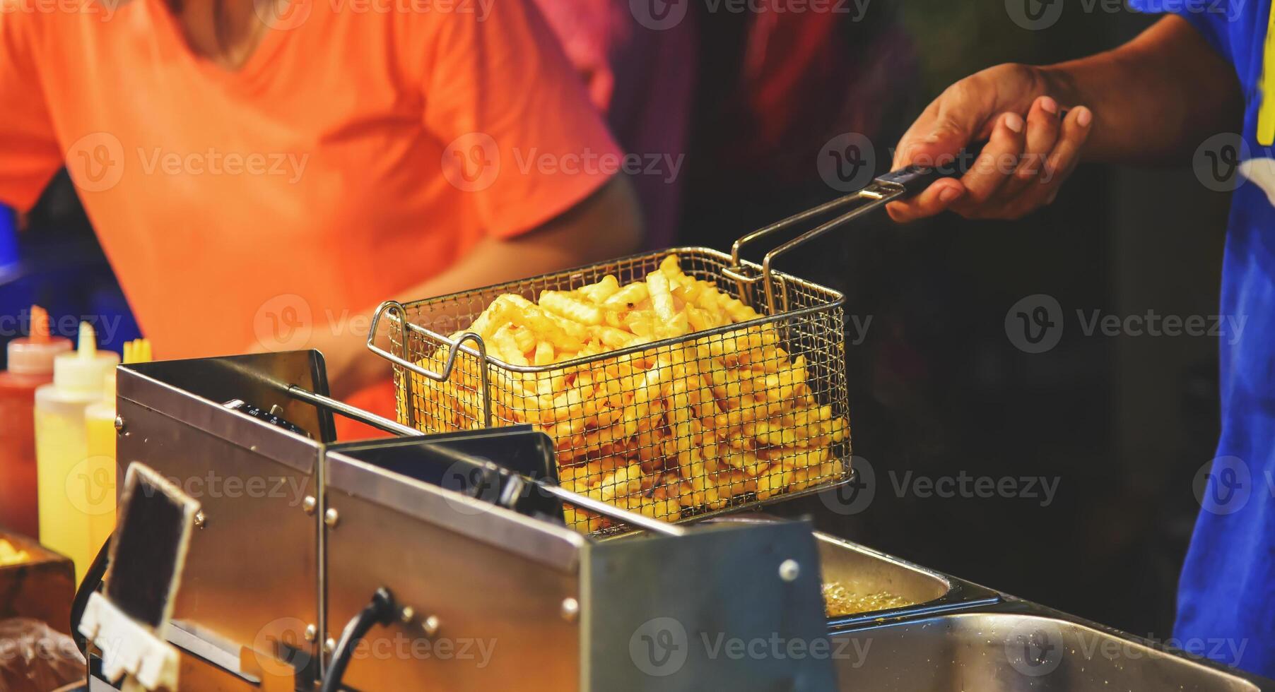 empleados fritura francés papas fritas con caliente aceite. de venta comida en el calle. foto