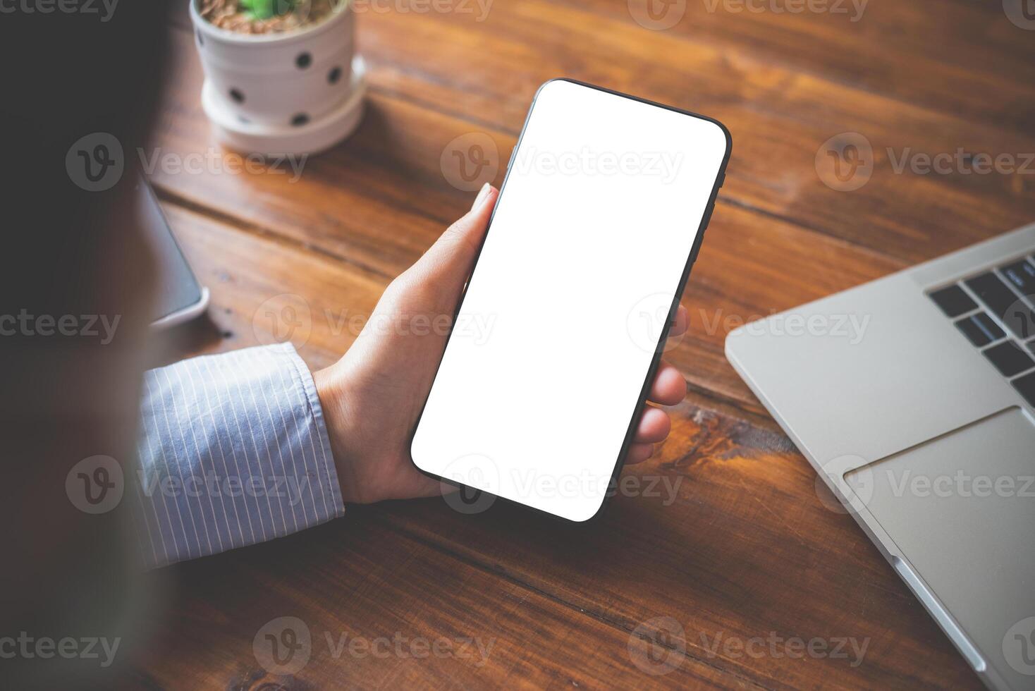 close-up mockup image of  hand holding black mobile phone with blank white  in desk work for home. photo