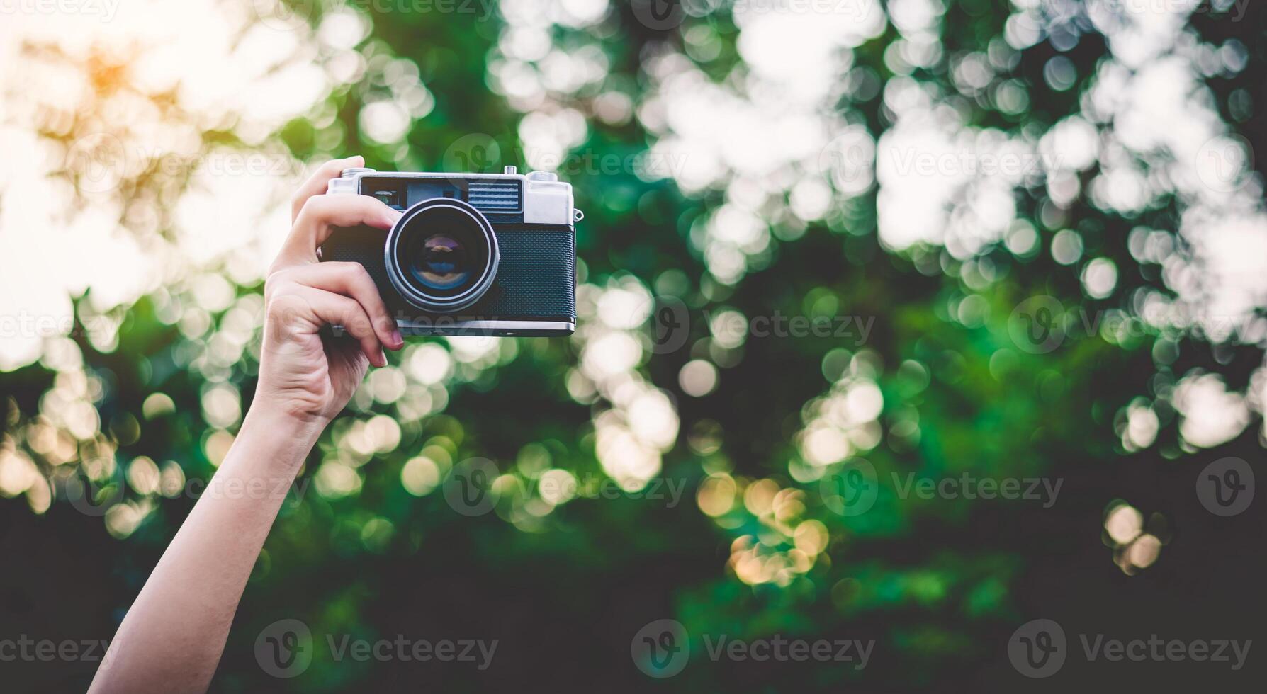 The hand that is holding up holds the old camera to take a picture. photo