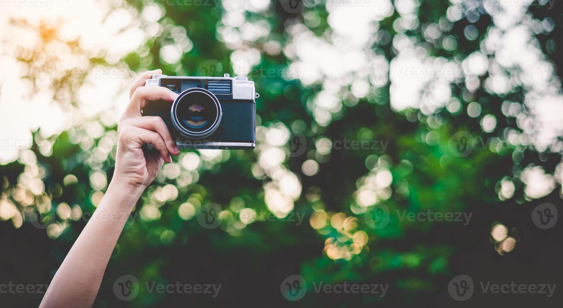 el mano ese es participación arriba sostiene el antiguo cámara a tomar un fotografía. foto