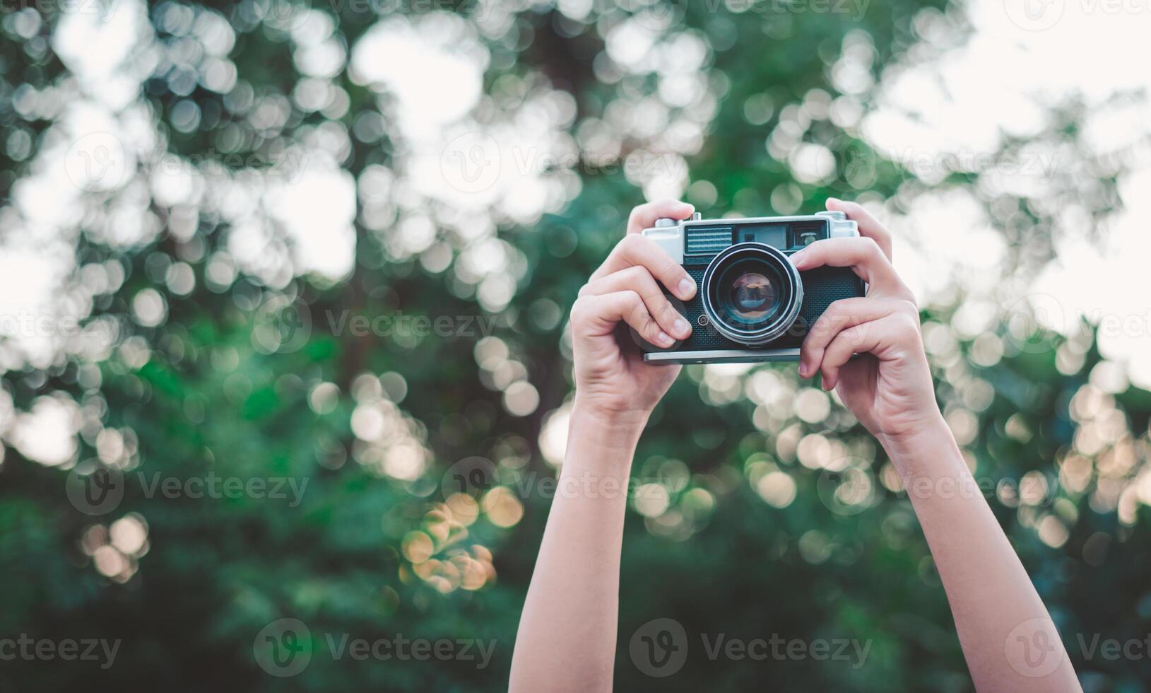 The hand that is holding up holds the old camera to take a picture. photo