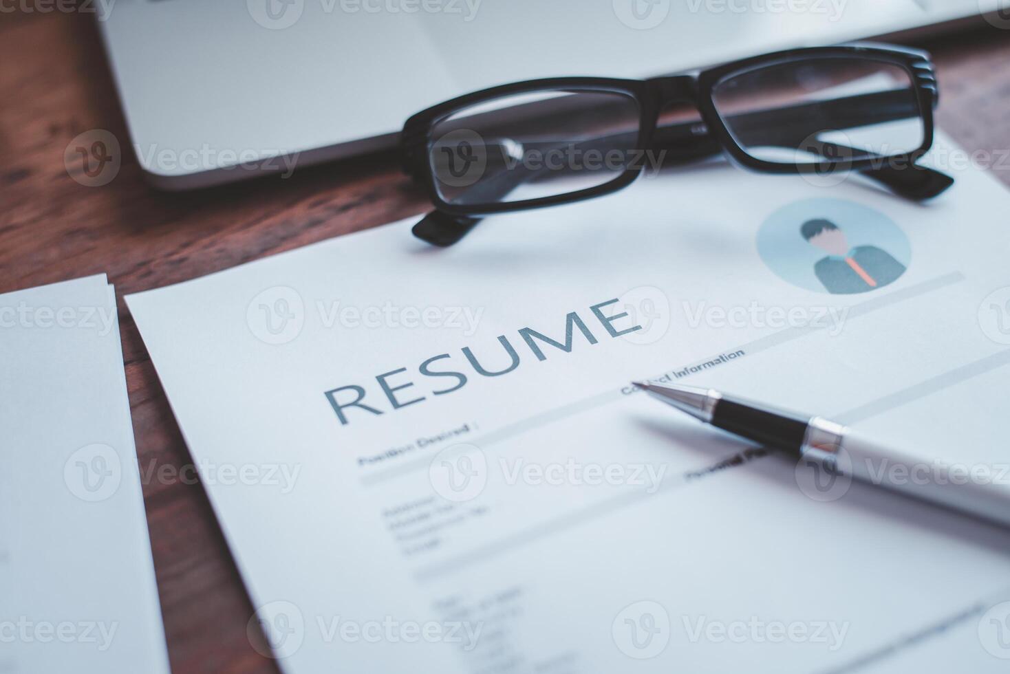 Personal resume documents placed on the working desk consisting of laptops, pens, job searching and job applications. photo