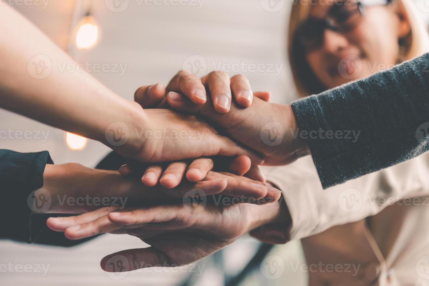 Hands of business people come together in a stack of hands to symbolize collaboration, teamwork to achieve goals and success. photo
