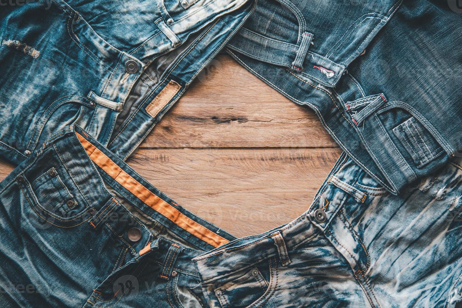 Several jeans are placed on the wooden floor. photo