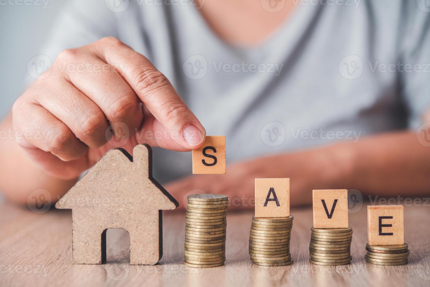 Hands are holding the matching S letter, SAVE on coins are stacked and the home are placed on the floor. - Savings Ideas for home photo