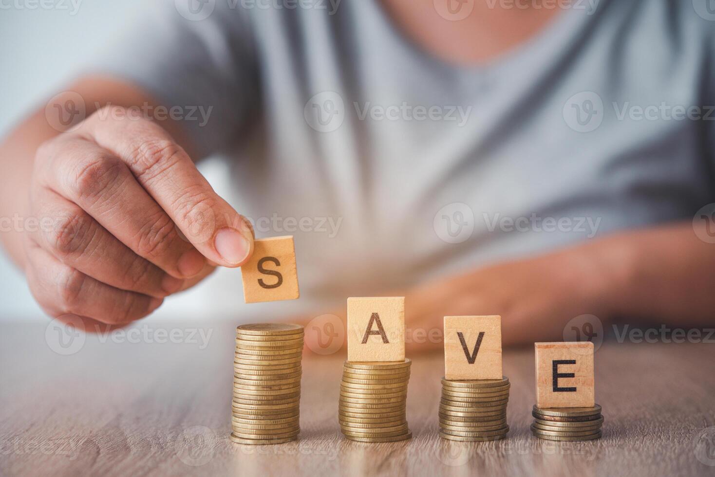 Hands holding the S letter on the coins are staggered and have  SAVE  wooden letters placed on the wood floor. - Savings Ideas for Increasing Volume photo