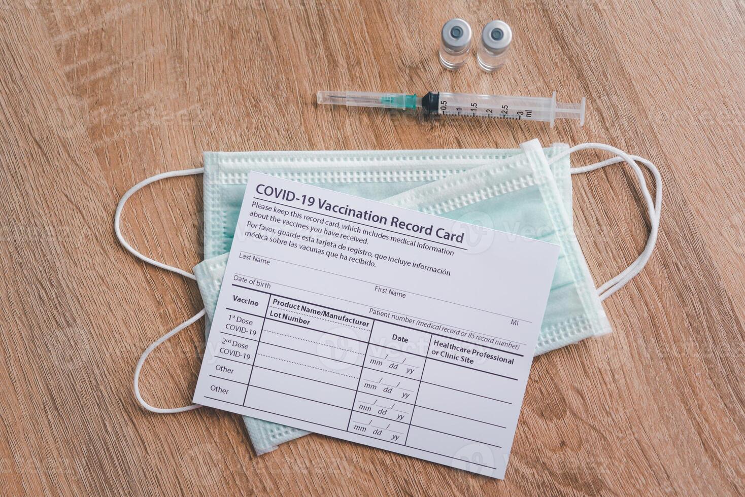 Coronavirus vaccination record card is placed on a wooden floor with a vaccine syringe .patient who has already been vaccinated with Coronavirus .Coronavirus prevention photo
